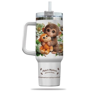 May include: White tumbler with a handle, featuring a cartoon illustration of two monkeys hugging, surrounded by flowers. The tumbler has a clear lid and a straw. The text "Punch Monkey Adventure Buddy" is printed on the tumbler.