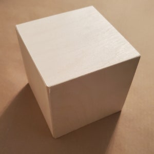 May include: A white, square-shaped wooden box with a smooth, painted surface.