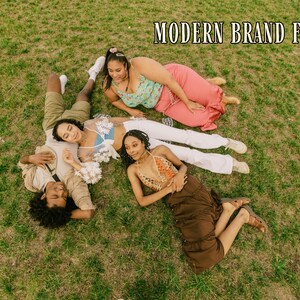 May include: An overhead shot of four people lying on green grass. They are wearing various outfits, including a crochet top, a floral top, and a brown skirt. The text "MODERN BRAND FEEL" is at the top of the image.