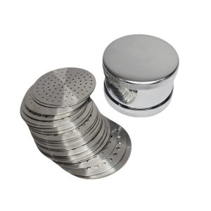 Könnte beinhalten: Ein Stapel silberfarbener, perforierter Metallscheiben und ein glänzender, verchromter zylindrischer Gegenstand mit flacher Oberseite. Die Scheiben haben kleine Löcher und sind in einem leicht gebogenen Haufen angeordnet.