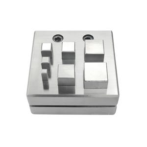 May include: A silver metal forming block with various square and rectangular protrusions. The block has a flat, rectangular base and a series of evenly spaced, raised square and rectangular shapes of varying sizes. The surface is smooth and reflective.