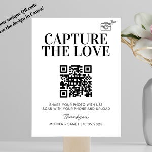Op de afbeelding: Een wit bord met de tekst "CAPTURE THE LOVE" en een QR-code. Hieronder staat "DEEL JE FOTO MET ONS! SCAN MET JE TELEFOON EN UPLOAD". Het bord staat op een houten voet, met rechts een vaas met bloemen.