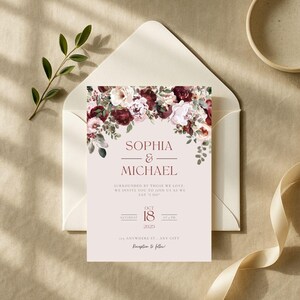 May include: A wedding invitation featuring the names "Sophia & Michael" in burgundy script, adorned with a floral arrangement of burgundy and cream-colored flowers. The invitation is set against a cream envelope, with the date "October 18, 2025" displayed.