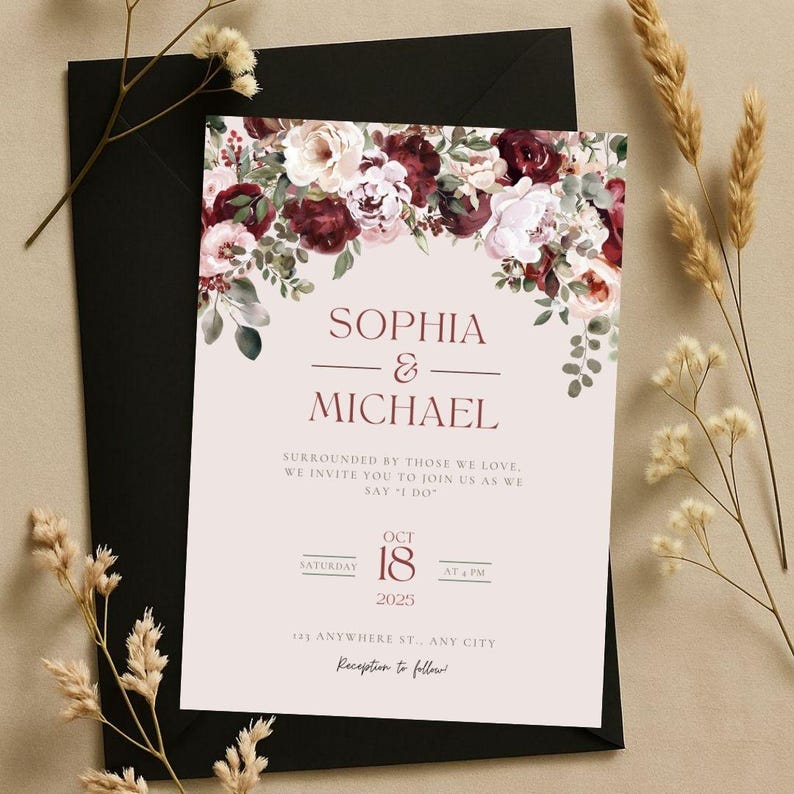 May include: Wedding invitation featuring the names "Sophia & Michael" in burgundy script, adorned with floral arrangements in burgundy, cream, and green. The invitation includes the date "October 18, 2025" and the words "Reception to follow". The invitation is set on a light pink background and placed on a black envelope.