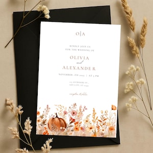 Op de afbeelding: Een trouwkaart met de namen Olivia en Alexander, met datum, tijd en locatie. Het ontwerp bevat een aquarel illustratie van pompoenen en herfstbloemen. De uitnodiging ligt op een zwarte envelop.