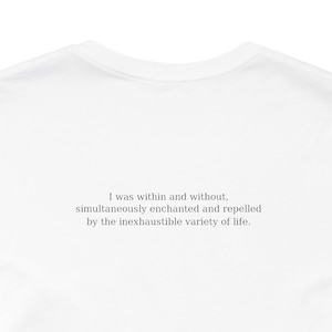 K&ouml;nnte beinhalten: Wei&szlig;es T-Shirt mit dem Text "I was within and without, simultaneously enchanted and repelled by the inexhaustible variety of life" in hellgrauer Schrift. Das T-Shirt hat einen Rundhalsausschnitt.