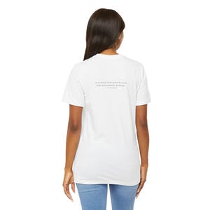 K&ouml;nnte beinhalten: Wei&szlig;es T-Shirt mit einem Zitat auf der R&uuml;ckseite. Das Zitat lautet: &bdquo;So we beat on, boats against the current, borne back ceaselessly into the past.&ldquo; - F. Scott Fitzgerald.