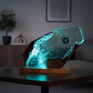Könnte beinhalten: Ein einzigartiges, beleuchtetes Kunstwerk aus Harz mit einem Star Wars TIE-Jäger-Design. Das Kunstwerk ist in klarem Harz mit einem leuchtend blauen Effekt eingeschlossen und steht auf einem Holzsockel. Enthält ein TIE-Jäger-Symbol und rote Laserfeuer.