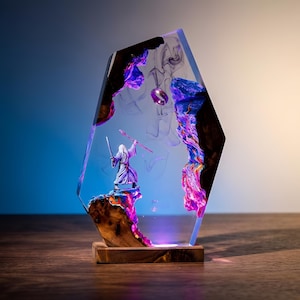 May include: A decorative resin sculpture featuring a miniature figure of a wizard with a staff and sword, standing on a wooden base. The sculpture has a clear, geometric shape with colorful, swirling accents and a ring suspended within.