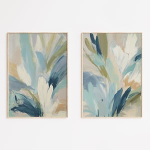 May include: Two vertical rectangular wall art prints featuring abstract brushstrokes in shades of navy blue, light blue, sage green, white, and beige. The compositions display layered, sweeping paint marks that create a sense of movement.