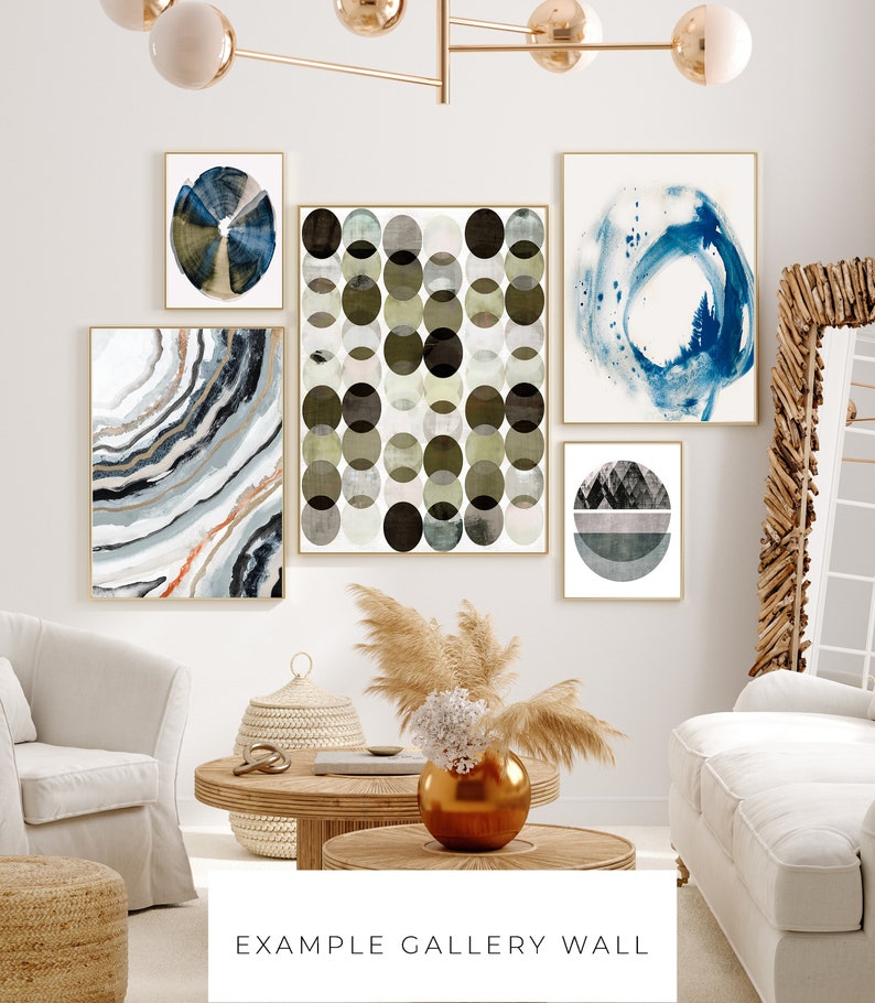May include: A gallery wall featuring five abstract art prints in various shades of blue, green, and gray. The prints are arranged in a staggered pattern on a white wall. The prints are framed in gold.
