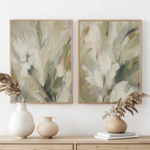 Puede incluir: Dos láminas de arte mural rectangulares con pinceladas abstractas en tonos verde salvia, crema y beige. Las obras están enmarcadas en madera clara y se acompañan de dos jarrones de cerámica y tallos de hierba de la pampa secos.