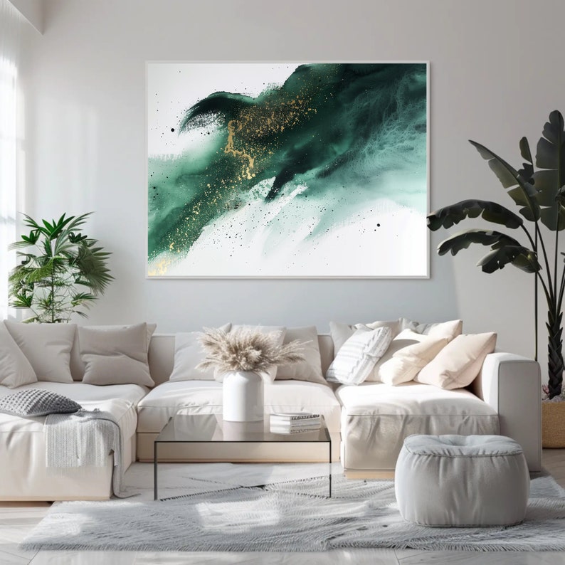 May include: A white sectional sofa with a green and gold abstract painting hanging above it. The sofa has a few throw pillows and a small glass coffee table in front of it. There is a green plant in a pot on the left side of the image and a green plant in a pot on the right side of the image.