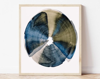 May include: A framed wall art print featuring a circular watercolor painting with radiating brushstrokes in shades of deep navy blue, muted olive green, and soft beige, centered on a white background within a light-toned wooden frame.