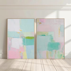 Puede incluir: Dos piezas de arte mural rectangular con composiciones abstractas de pintura en capas. La paleta de colores incluye rosa pastel suave, verde menta, amarillo pálido y blanco, aplicados con pinceladas visibles y técnicas de empaste.