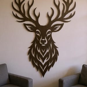 May include: A large, brown wooden deer head wall decor with intricate cut-out details. The deer head features large antlers and a detailed face, mounted on a white wall. The artwork is a decorative piece for home or cabin decor.