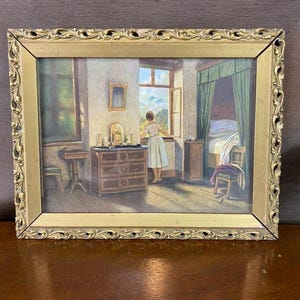 May include: A framed painting depicting a woman looking out a window in a bedroom. The painting has a gold ornate frame. The room features a dresser, a bed with a canopy, and a small table. The color palette includes greens, browns, and whites.
