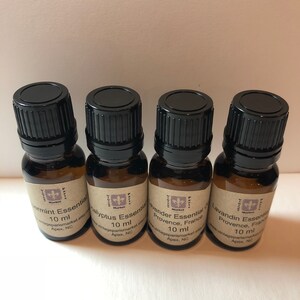 May include: Four small brown glass bottles with black caps, each containing 10 ml of essential oil. The labels are brown with white text and a small purple flower logo. The labels read "Peppermint Essential Oil", "Eucalyptus Essential Oil", "Lavender Essential Oil Provence, France", and "Lavandin Essential Oil Provence, France".