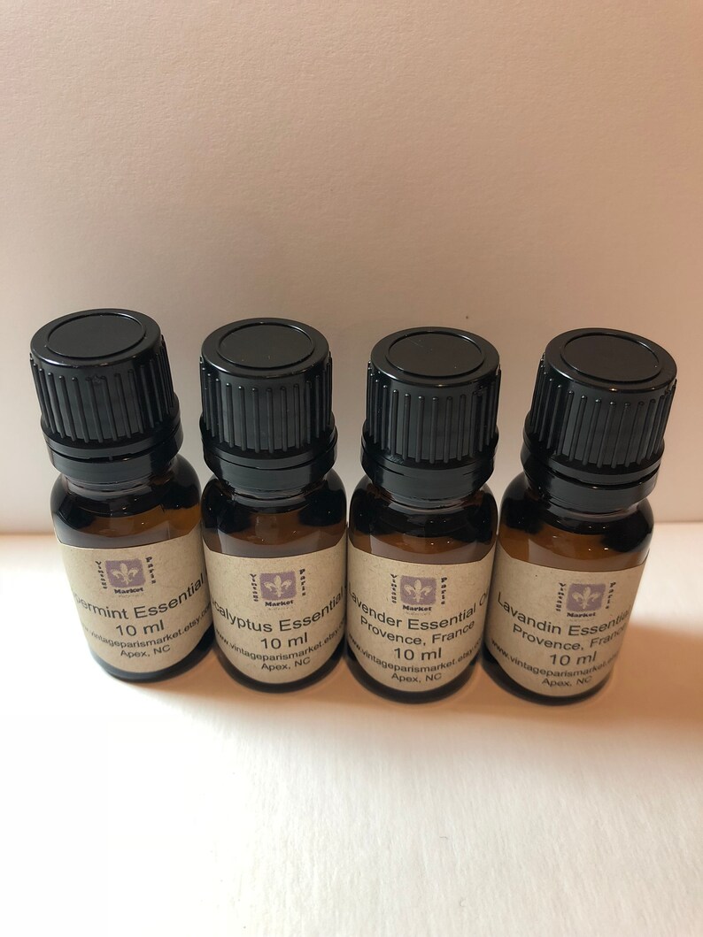 May include: Four small brown glass bottles with black caps, each containing 10 ml of essential oil. The labels are brown with white text and a small purple flower logo. The labels read "Peppermint Essential Oil", "Eucalyptus Essential Oil", "Lavender Essential Oil Provence, France", and "Lavandin Essential Oil Provence, France".