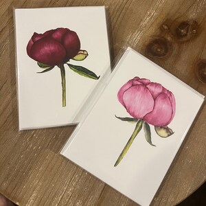 May include: Two blank greeting cards with watercolor illustrations of pink and burgundy peonies.