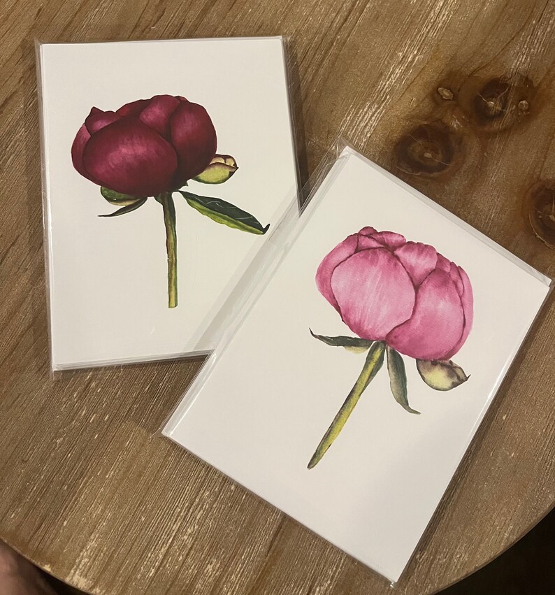 May include: Two blank greeting cards with watercolor illustrations of pink and burgundy peonies.