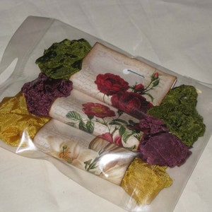 May include: A clear plastic bag filled with fabric scraps. The scraps are in shades of green, burgundy, and yellow. There are also four vintage-style cards with floral designs and the text "The Garden".