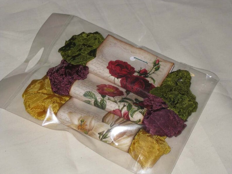 May include: A clear plastic bag filled with fabric scraps. The scraps are in shades of green, burgundy, and yellow. There are also four vintage-style cards with floral designs and the text "The Garden".