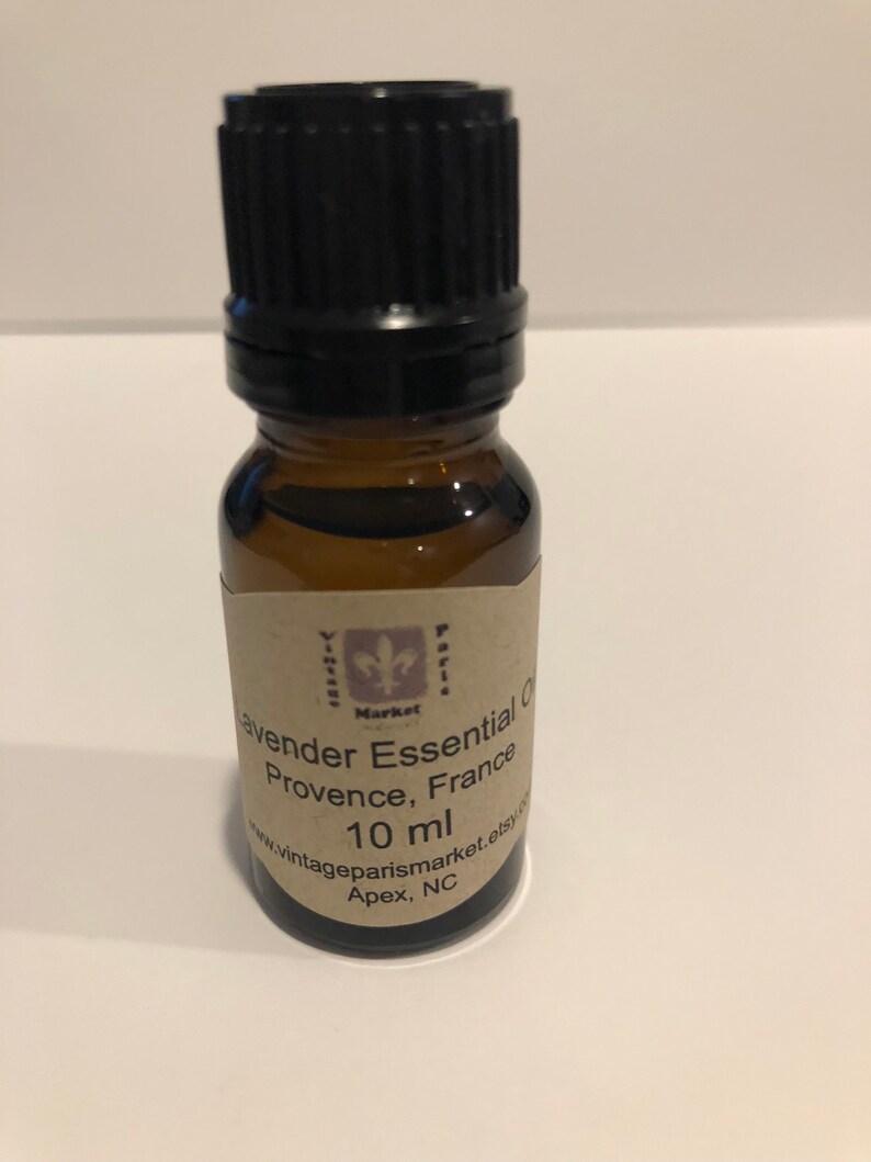 May include: A small brown glass bottle with a black cap, containing lavender essential oil. The label reads "Lavender Essential Oil, Provence, France, 10 ml, www.vintageparismarket.etsy.com, Apex, NC".