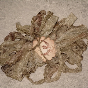 May include: A bundle of gold and brown silk ribbon with a small tag tied to it. The tag has a brown bird design and the number 5 printed on it.