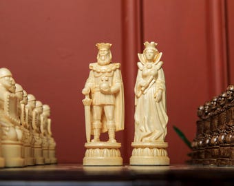 Op de afbeelding: Een schaakspel met ingewikkeld gesneden ivoorkleurige stukken. De koning en koningin staan op de voorgrond, met andere stukken erachter opgesteld. De achtergrond is effen bruin.