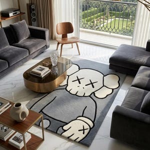 May include: A modern living room featuring a gray rug with a cartoon character design. The room includes gray sofas, a wooden chair, a coffee table, and a side table. A large window offers a view of a cityscape.