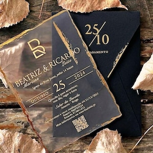 Può includere: Un invito di nozze rettangolare in acrilico trasparente con bordi irregolari dipinti in oro, caratterizzato da testo dorato e un codice QR. Il testo include i nomi Beatriz e Ricardo, la data 25 ottobre 2024 e i dettagli del luogo.