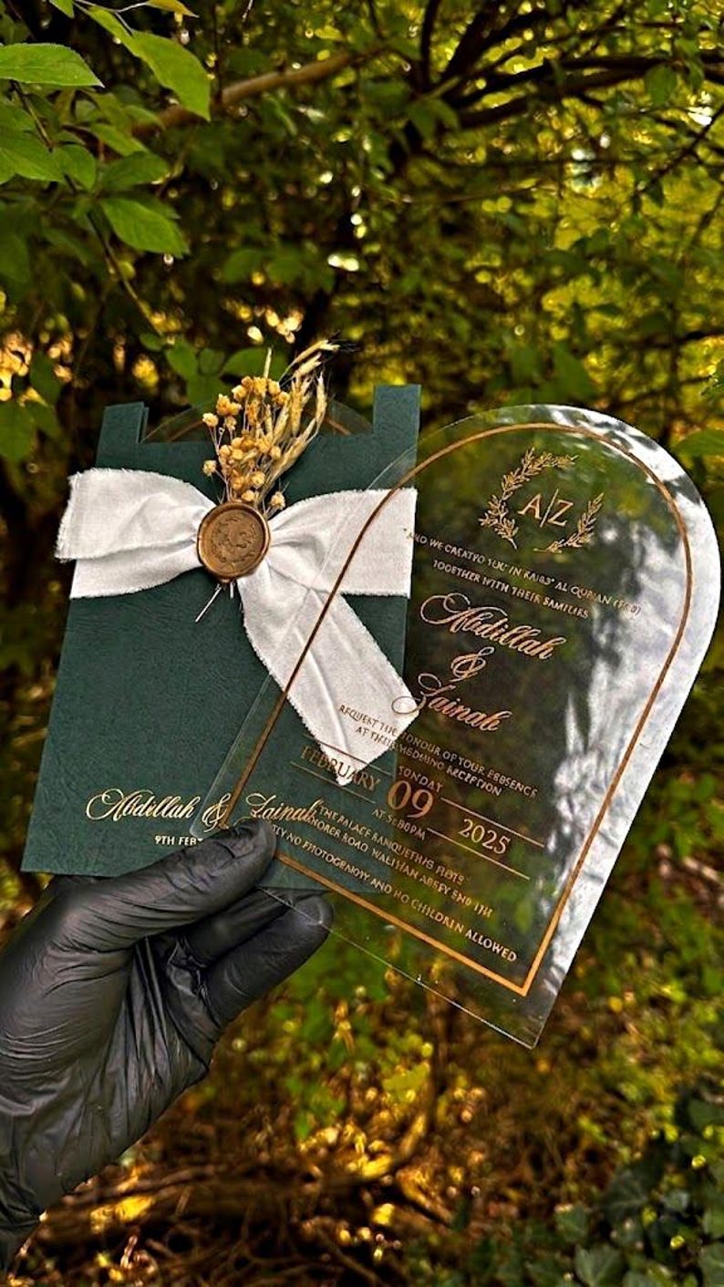 Puede incluir: Elegante invitaci&oacute;n de boda con una tarjeta verde oscuro con letras doradas, una cinta blanca y un sello dorado. Una tarjeta acr&iacute;lica transparente con texto dorado est&aacute; superpuesta. La invitaci&oacute;n incluye los nombres Abdillah & Zainab y la fecha 09 de febrero de 2025.