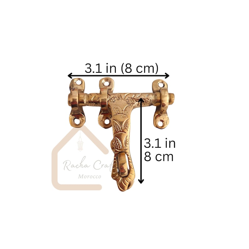 May include: A brass door latch, measuring 8 cm in length and height, with floral and leaf detailing. The latch has a decorative handle and mounting holes. The product is from Racha Craft Morocco.