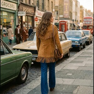 Puede incluir: Una chaqueta de ante color canela con largos flecos en la parte superior de la espalda y a lo largo del dobladillo inferior, combinada con vaqueros azules y un bolso de hombro de cuero marr&oacute;n. La chaqueta tiene un corte estructurado.