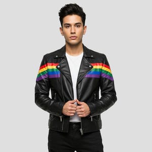 May include: A black motorcycle jacket featuring a horizontal rainbow stripe pattern across the chest and sleeves. The jacket includes a notched lapel, silver-toned metal zippers on the front and pockets, and a white shirt worn underneath.