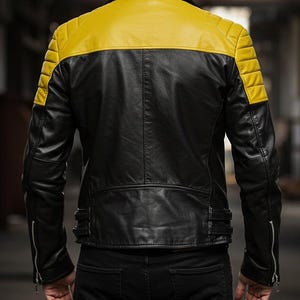 May include: Black leather jacket with a yellow shoulder and upper back panel. The jacket has quilted shoulder detailing, a zipper closure, and a tailored fit. The model is wearing black jeans.