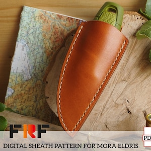 Puede incluir: Una funda de cuero marrón claro con costuras blancas, diseñada para un cuchillo Mora Eldris. La funda se muestra sobre una superficie de madera con un mapa y vegetación en el fondo. El texto "DIGITAL SHEATH PATTERN FOR MORA ELDRIS" es visible.