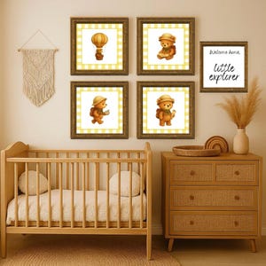 Puede incluir: Una escena de guardería con una cuna de madera, una cómoda y obras de arte enmarcadas. La obra de arte incluye cuatro impresiones cuadradas con ilustraciones de osos de peluche y un letrero que dice "Welcome home, little explorer."