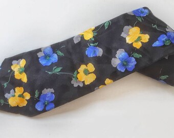 May include: A black silk tie with a floral pattern featuring yellow and blue flowers.