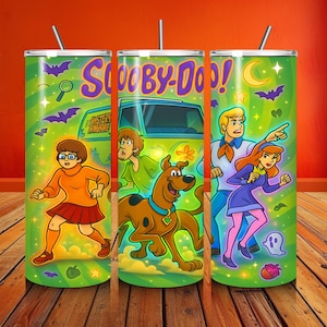 Pode incluir: Três canecas verdes com tema Scooby-Doo com canudos. Cada caneca apresenta um personagem ou cena diferente de Scooby-Doo. O texto "Scooby-Doo!" é exibido na caneca do meio. O fundo é verde com morcegos, estrelas e uma lua crescente.