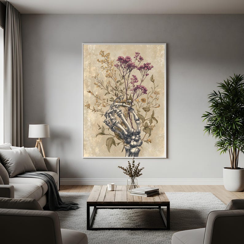 May include: A framed art print featuring a skeletal hand holding a bouquet of flowers. The flowers are a mix of purple and yellow, set against a beige background. The artwork has a vintage, gothic aesthetic, suitable for home decor.