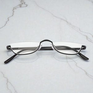 May include: Rimless spectacles with a black frame. The glasses feature a half-frame design, with the top of the lenses supported by a thin, curved black metal frame. The arms are also black.