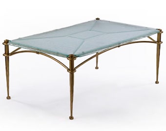 Puede incluir: Una mesa de centro rectangular con una tapa de vidrio texturizado y un marco de metal color bronce. La mesa tiene cuatro patas y una estructura de soporte curvada. La tapa de vidrio tiene un diseño rectangular central.