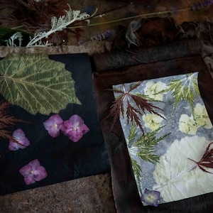 Peut inclure: Une composition artistique avec des feuilles et des fleurs pressées sur des fonds sombres. L'image présente une grande feuille verte, des feuilles d'érable bordeaux et des fleurs d'hortensia violettes. Une deuxième pièce affiche un motif similaire sur fond gris clair.