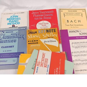 May include: A collection of vintage music books, including piano and clarinet methods. Titles include "John Brimhall Piano Method," "John Thompson's Modern Course for the Piano," and "Schaum Keynote Music Speller." The books are in various colors.