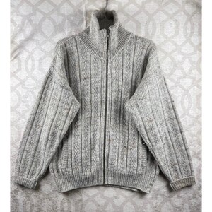 May include: A light gray zip-up sweater featuring a vertical ribbed knit pattern and a high mock neck collar. The garment is crafted from a textured, heathered yarn with subtle flecks of brown and tan throughout, including long sleeves and ribbed cuffs.