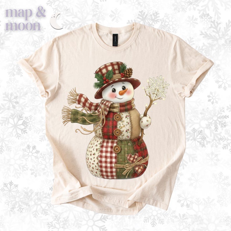 以下が含まれることがあります： クリーム色のTシャツ。雪だるまのデザイン。雪だるまはチェック柄の帽子とスカーフを身に着け、雪の結晶を持っています。デザインには赤、緑、ベージュのパッチワーク模様が組み込まれており、人参の鼻とボタンのディテールがあります。「map & moon」のブランド名が左上にあります。