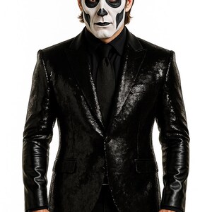 May include: A person in a black sequined blazer, black shirt, and tie, with a skull-like face painted in white and black. The blazer has leather sleeves. The person is standing against a white background.