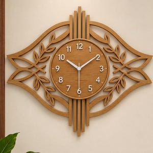 May include: A light brown wooden wall clock featuring a circular face with white Arabic numerals and white hands. The clock is surrounded by a decorative frame with symmetrical leaf patterns and vertical slats extending from the top and bottom.